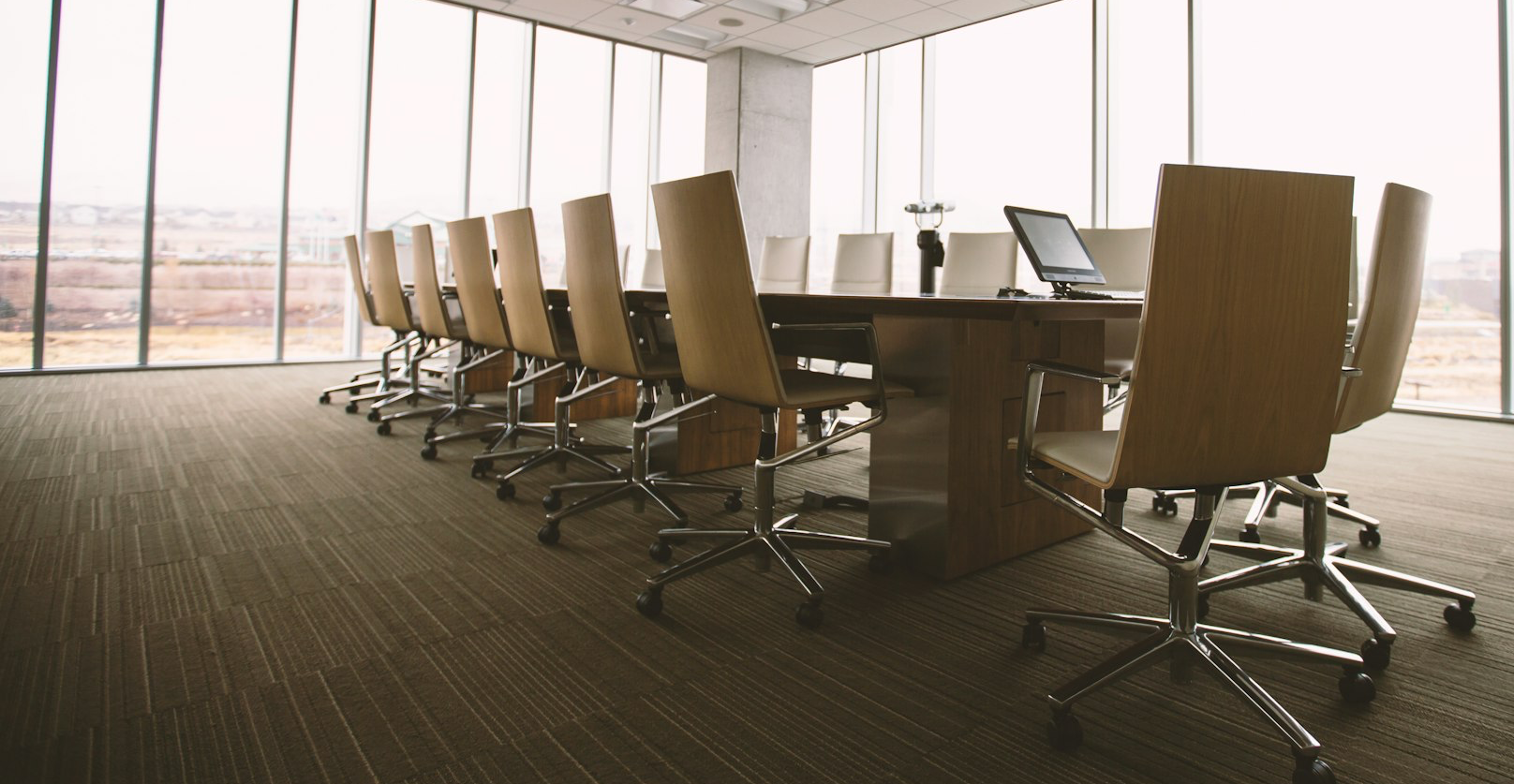 oval brown wooden conference table and chairs inside conference room